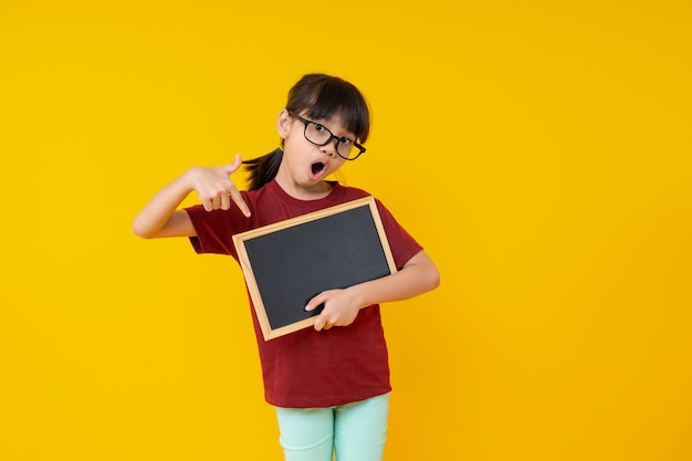 Estudante asiática nova na camisa vermelha que prende o quadro-negro pequeno em branco