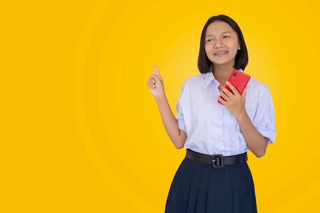 Estudante asiático em uniforme usar telefone inteligente vermelho.