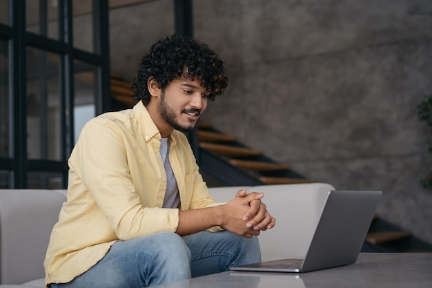 Estudante asiático sorridente usando laptop estudando tendo aula on-line sentado em casa Conceito de educação