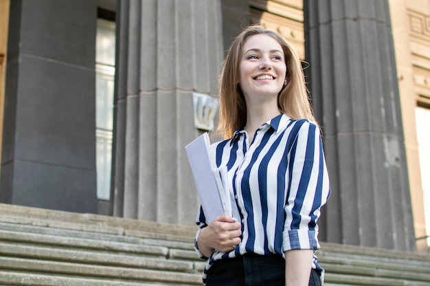 Estudante bonito em pé perto da universidade