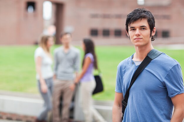 Estudante bonito posando enquanto seus colegas estão falando