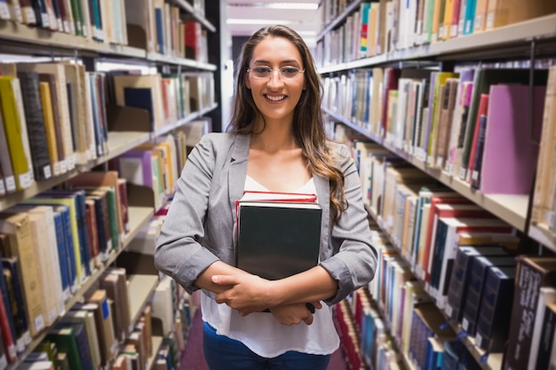 Estudante bonito que escolhe um livro na biblioteca