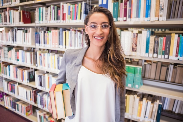 Estudante bonito que guardara livros na biblioteca