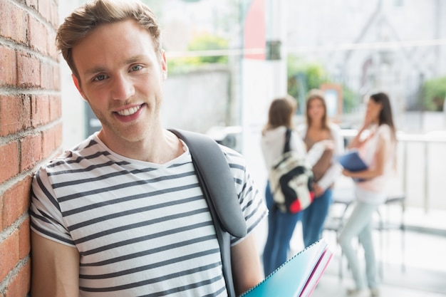 Estudante bonito sorrindo e segurando blocos de notas