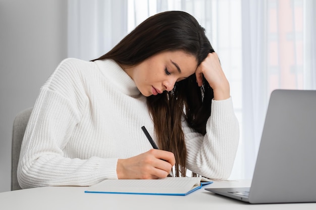 Estudante cansado faz anotações no livro se prepara para um exame ou faz lição de casa