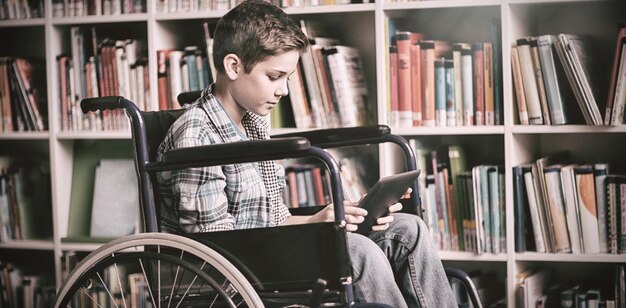 Foto estudante com deficiência usando tablet digital na biblioteca