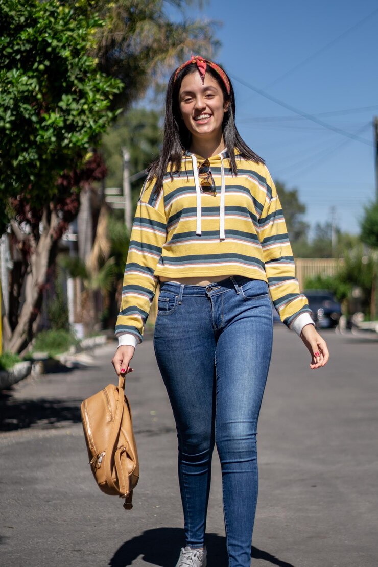 Foto estudante com roupas à moda a atravessar a estrada, uma rapariga elegante e hipster a usar roupas grandes.