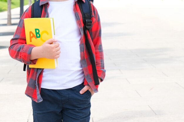 Estudante com um livro na mão na rua a caminho da escola. De volta à escola.