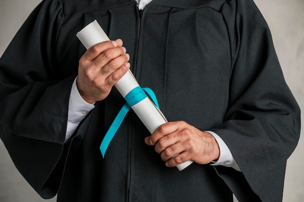 Estudante com vestido de formatura segurando seu diploma