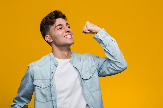 Estudante considerável novo que veste uma camisa da sarja de nimes que aumenta o punho após uma vitória, conceito do vencedor.