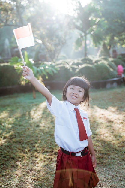 Estudante da escola indonésia segurando bandeira durante o dia da independência