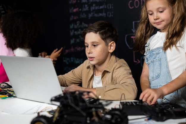 Estudante de camisa castanha e estudante de bib branco assistem laptop e discutem erudição