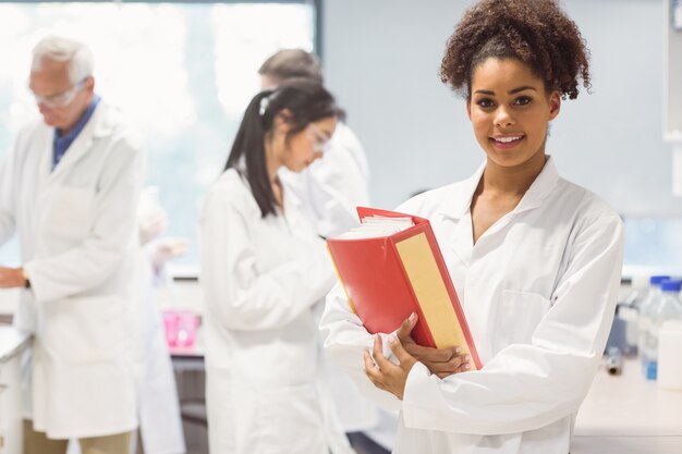 Estudante de ciência segurando grande pasta no laboratório