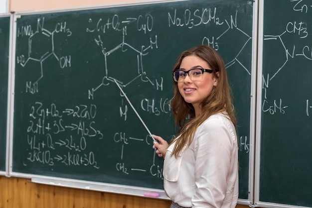 Estudante de ciências do sexo feminino com óculos explica a aula de química na escola. Educação