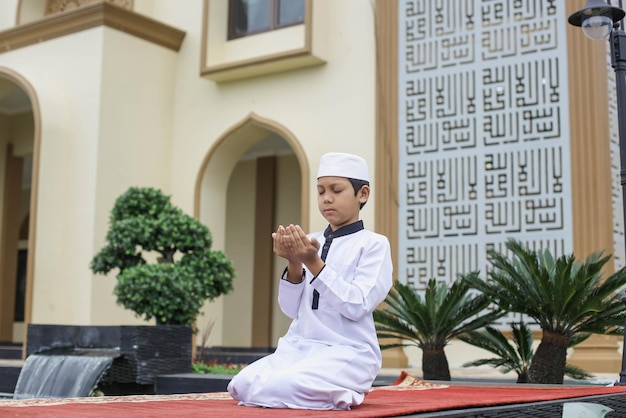 Estudante de internato islâmico reza a Deus no pátio da mesquita