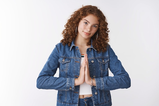 Foto estudante de jovem ruiva caucasiana atraente de aparência séria vestindo jaqueta jeans pressione as palmas das mãos juntas rezando suplicando faça um desejo pedindo favor implorando ajuda em pé fundo branco