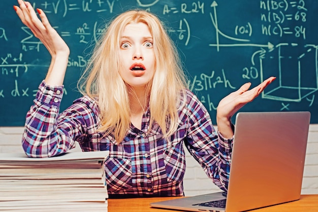 Estudante de mulher irritada emocional gritando no fundo do quadro-negro da sala de aula Jovem estudante universitário na preparação para o exame difícil na sala de estudo parecendo cansado e cansado