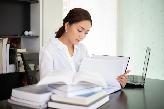 Estudante de mulheres asiáticas sorrindo e lendo um livro para relaxamento e exame final