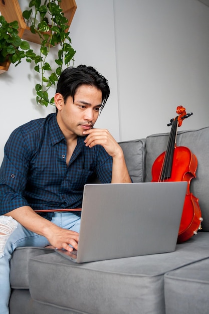 Estudante de música jovem hispânico assistindo aulas no laptop