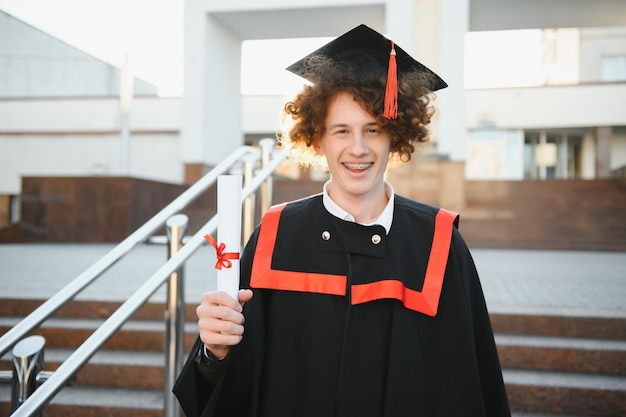 Estudante de pós-graduação animado em vestido com as mãos levantadas segurando o diploma