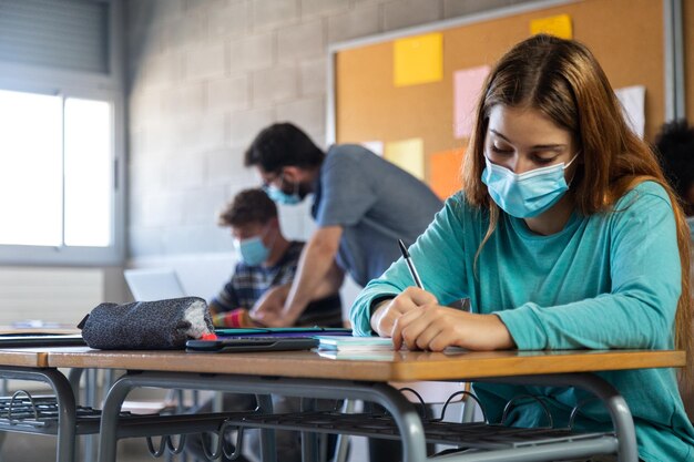 Foto estudante do ensino médio usando máscara facial na aula fazendo trabalhos de casa