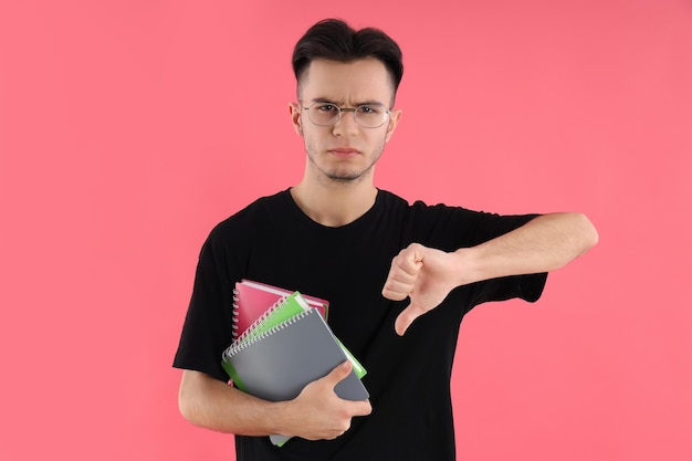 Estudante do sexo masculino com notebooks em fundo rosa