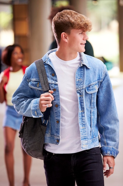 Estudante do sexo masculino sorridente na universidade ocupada ou prédio da faculdade