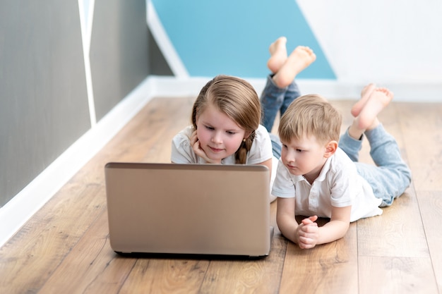 Estudante e garota estudando em casa com o notebook laptop digital e fazendo lição de casa da escola.