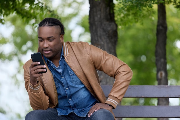 Estudante elegante afro-americano lê entusiasticamente ebook no smartphone