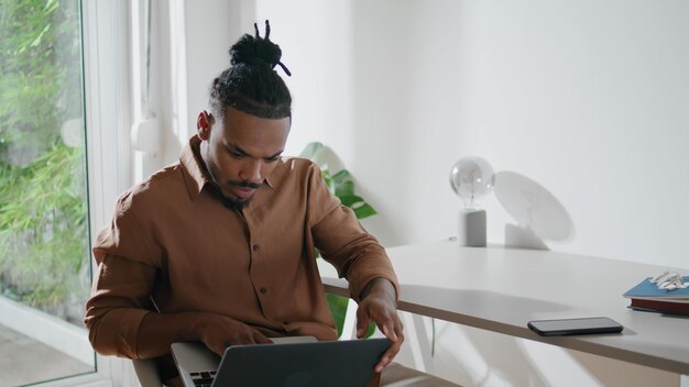 Foto estudante envolvido assistindo homem focado no local de trabalho do laptop olhando a tela em casa