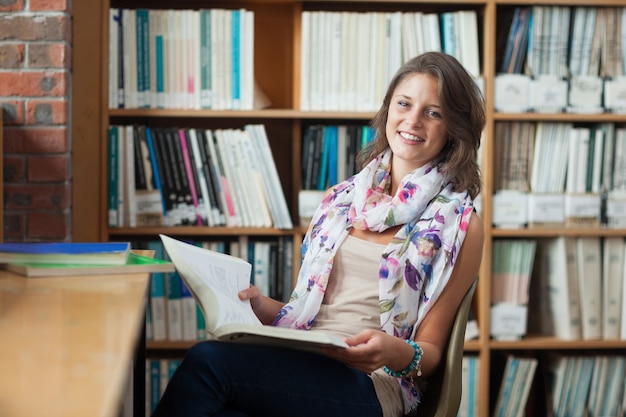 Estudante feliz com um livro na biblioteca