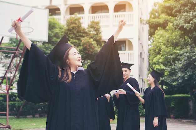 Estudante Feliz Permanente Com Diploma Com Amigos Atrás. Comemorando o sucesso, conceito de objetivo de educação.