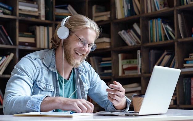 Estudante feliz rindo usa fone de ouvido falando videochamada no laptop