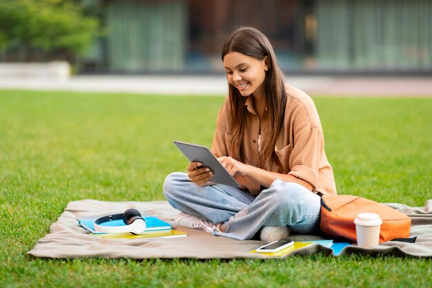 Estudante feliz scrolling em tablet digital sentado no campus