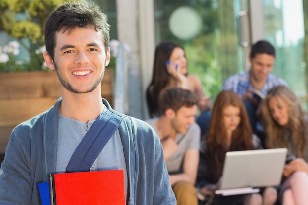 Estudante feliz sorrindo para a câmera lá fora no campus