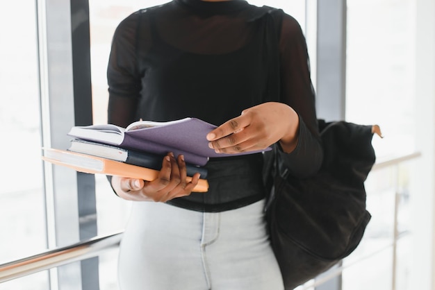 Estudante feminina muito afro-americana com mochila e papelada na sala de aula da universidade