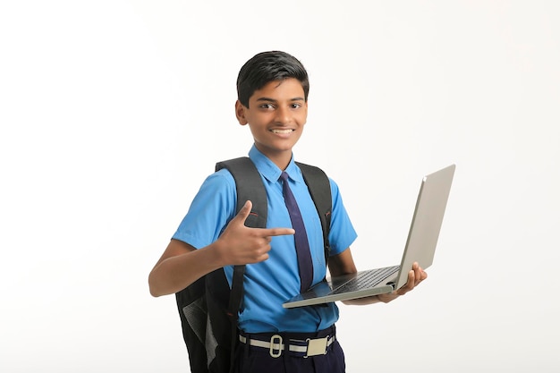 Estudante indiano de uniforme e usando laptop em fundo branco