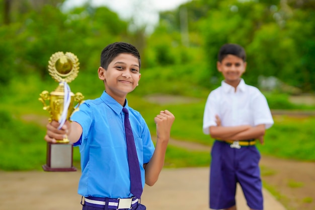 Estudante inteligente levantando seu troféu como vencedor em uma competição escolar e comemorar com seu amigo.