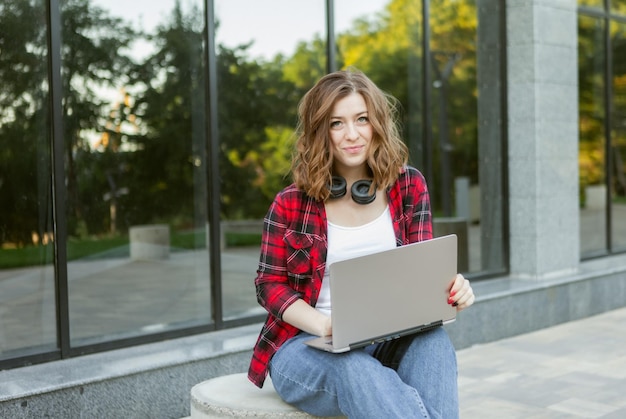 Estudante jovem alegre usando laptop ao ar livre. Trabalho a distância ou conceito de educação