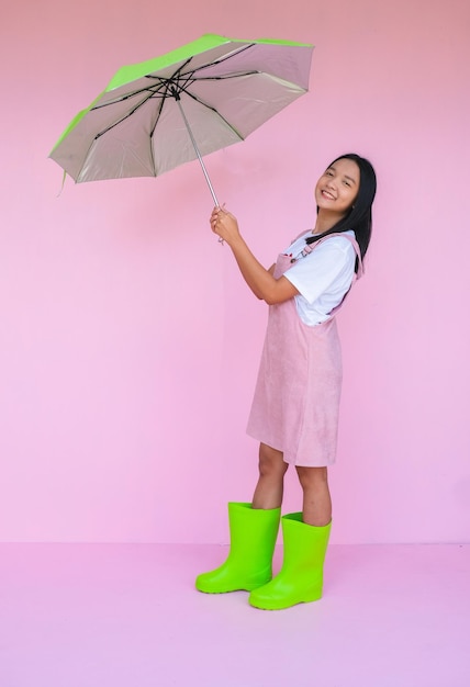 Estudante jovem com guarda-chuva verde no fundo rosa