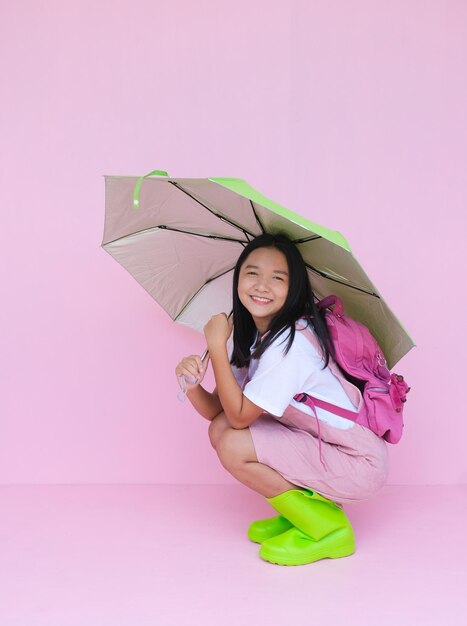 Estudante jovem com guarda-chuva verde no fundo rosa