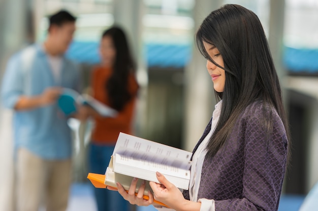 Estudante jovem com livros nas mãos no campus.