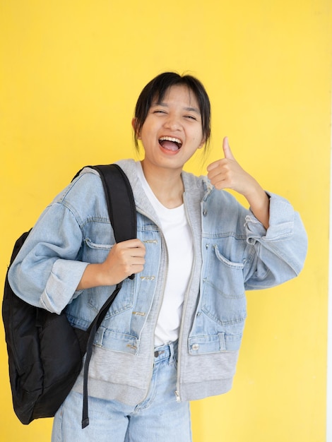 Foto estudante jovem com mochila em fundo amarelo