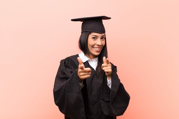 Estudante jovem Latina, sentindo-se feliz, legal, satisfeito, relaxado e bem sucedido, apontando