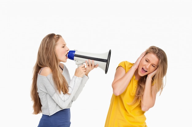 Estudante loiro gritando com um alto-falante em outra garota