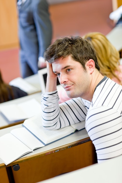 Estudante masculino entediado durante uma aula universitária