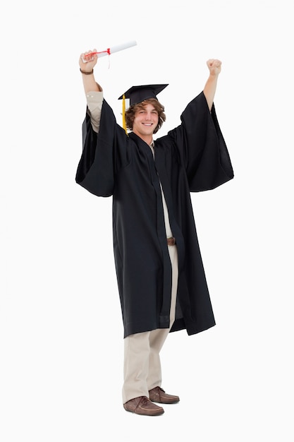 Estudante masculino na veste de graduação levantando os braços