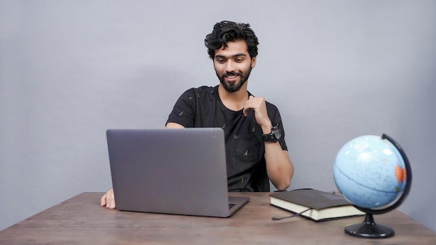 estudante masculino ponto na tela do laptop fundo cinza modelo indiano do paquistanês