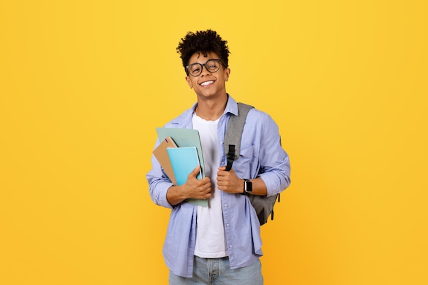 Estudante negro feliz com livros e mochila .