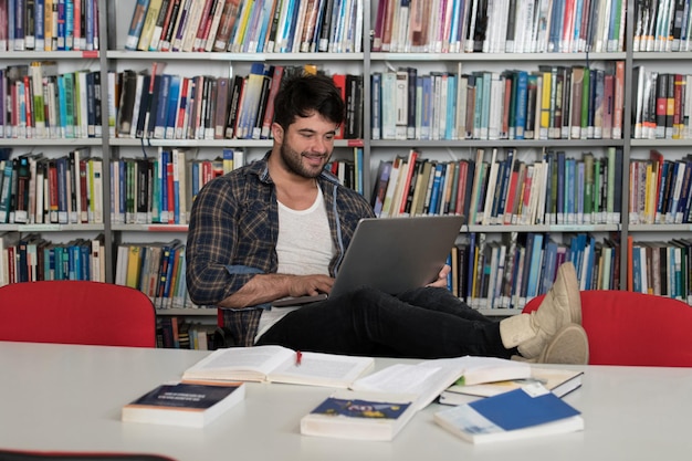 Estudante Preparando Exame e Aprendendo Lições na Biblioteca Escolar Fazendo Pesquisa no Laptop e Navegando na InternetxANa Biblioteca